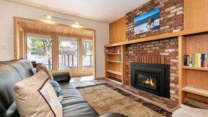 A cozy living room with a fireplace, a leather sofa, and a bookshelf. - Agate Bay 3BDR, Walking Distance to the Beach! (Tahoe Vista)