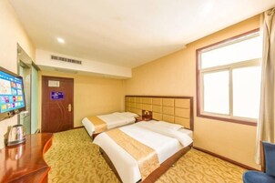 Habitación de hotel con dos camas, un escritorio con computadora y un ventanal grande.