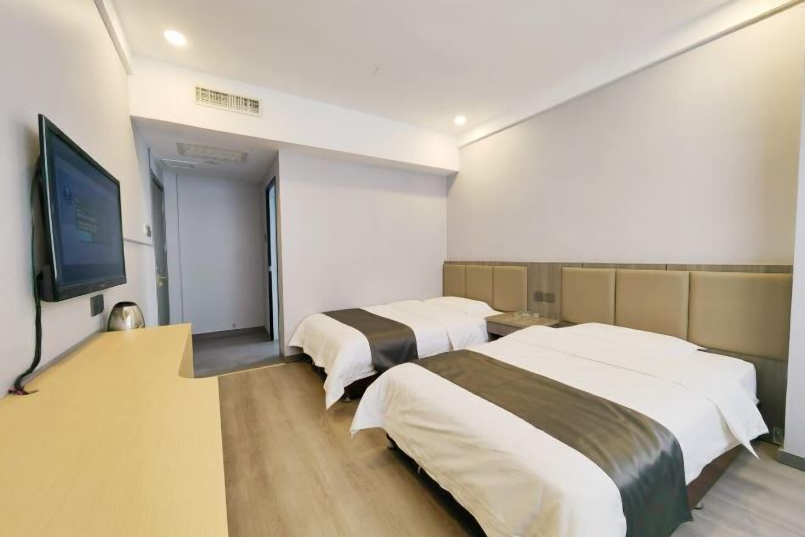 Ein Hotelzimmer mit zwei Betten, einem Schreibtisch und einem Fernseher.
