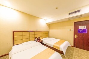 Habitación de hotel con dos camas, cabecero de madera, suelo alfombrado, puerta con un cartel y rejilla de ventilación en la pared.