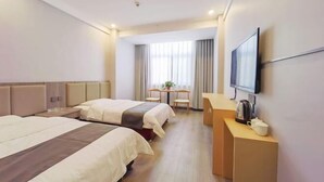 A hotel room with two beds, a desk, a TV, and a window with curtains.