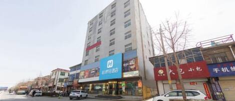 A multi-story building with commercial establishments on the ground floor, including a pharmacy and a mobile phone store.