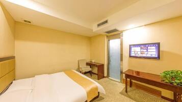 Une chambre d’hôtel avec un lit, un bureau, une chaise, une télévision et une porte.