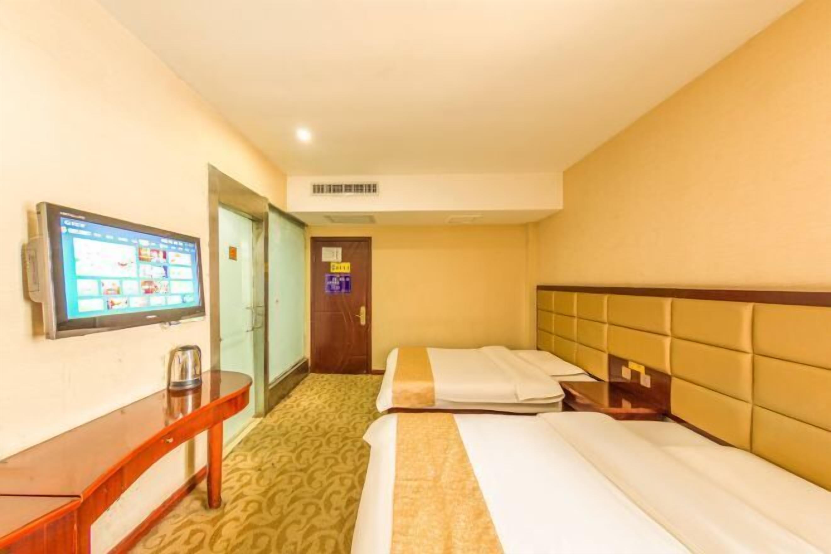 A hotel room with a bed, a desk, a television, and a door.