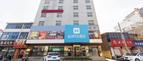 A hotel with a prominent blue sign, multiple floors, and a parking area in front.