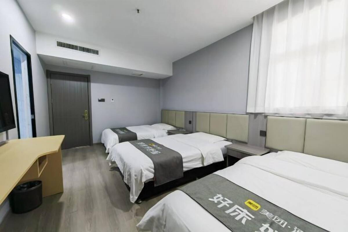 A hotel room with two beds, a desk, and a window with curtains.