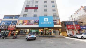 A hotel with a prominent blue sign, multiple floors, and a variety of shops on the ground floor.