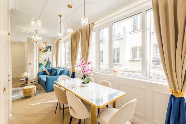 A spacious living room with a dining area, large windows, and a view of the city.