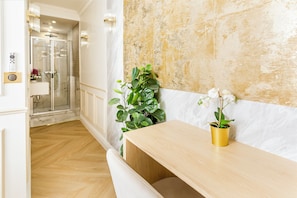 A bathroom with a glass shower enclosure, a marble wall, and a wooden bench.