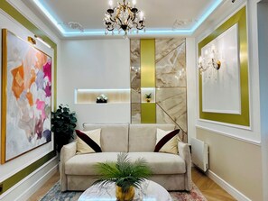 A modern living room with a sofa, a coffee table, and a chandelier. - Merveil - Luxury Suite - Marais - Charlot (Paris)