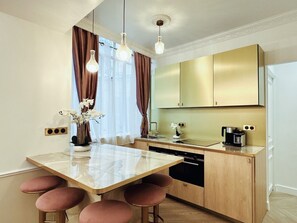 A modern kitchen with a marble countertop, wooden cabinets, and pendant lighting. - Merveil - Luxury Suite - Marais - Charlot (Paris)