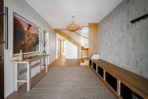 A modern interior with a wooden bench, a staircase, and a textured wall.