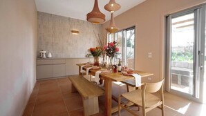 Eine moderne Küche mit großem Esstisch, Holzstühlen und Pendelleuchten.