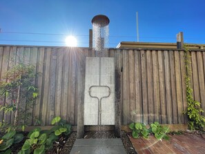 A water feature with a fountain in a garden setting.