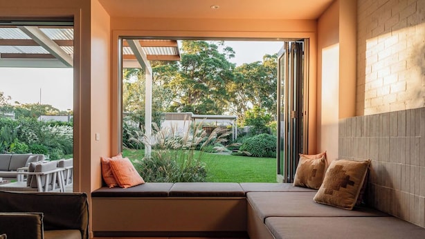 Un salon moderne avec un canapé, une table basse et une vue sur un jardin, visible à travers une porte vitrée.