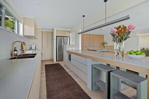 A modern kitchen with a large island, stainless steel appliances, and a vase with flowers on the counter.