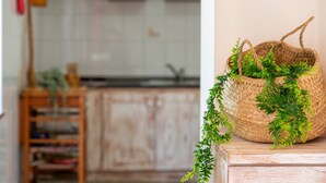 A kitchen with wooden cabinets, a wooden table, and a woven basket with green foliage.