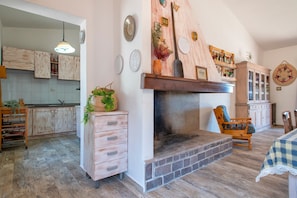 Una cucina rustica con mobili in legno, un camino e un'area pranzo con tovaglia a quadri.