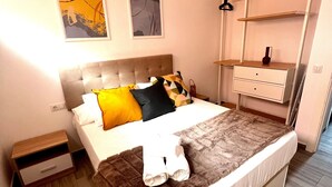A bedroom with a bed, a nightstand, a dresser, and two wall-mounted shelves. - Vacation Apartment 'Bluebell L6' with Wi-Fi and Air Conditioning (Armeñime)
