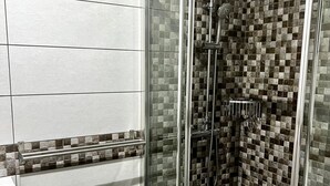 A shower with a glass door, a tiled wall, and a metal handrail. - Vacation Apartment 'Bluebell L6' with Wi-Fi and Air Conditioning (Armeñime)