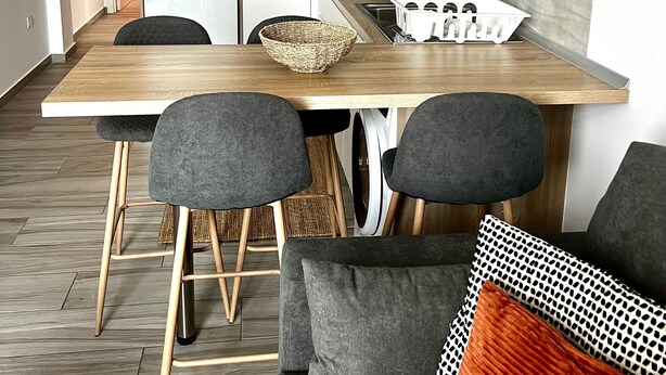 A modern kitchen with a wooden countertop, a built-in oven, and a sink. There are two chairs and a dining table. - Vacation Apartment 'Bluebell L6' with Wi-Fi and Air Conditioning (Armeñime)