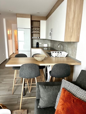 Une cuisine moderne avec un plan de travail en bois, un four encastré et un évier. On y trouve deux chaises et une table à manger.