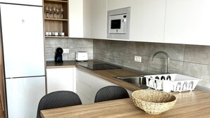 A modern kitchen with a wooden table, chairs, a microwave, and a sink. - Vacation Apartment 'Bluebell L6' with Wi-Fi and Air Conditioning (Armeñime)