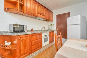 A kitchen with wooden cabinets, a microwave, an oven, and a refrigerator. - Holiday Home 'Rafalita' with Sea View, Wi-Fi and Air Conditioning (Torrox)