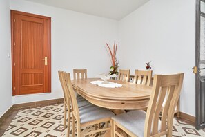 A dining area with a wooden table and chairs, a decorative vase, and patterned floor tiles. - Holiday Home 'Rafalita' with Sea View, Wi-Fi and Air Conditioning (Torrox)