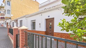 A building with a white facade, a brown door, and a brick base. - Holiday Home 'Rafalita' with Sea View, Wi-Fi and Air Conditioning (Torrox)