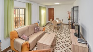 A living room with a sofa, a coffee table, a TV, a dining table with chairs, and a patterned floor. - Holiday Home 'Rafalita' with Sea View, Wi-Fi and Air Conditioning (Torrox)