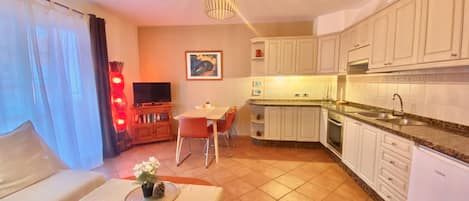 A compact living space with a kitchenette, a dining area, and a seating area with a sofa and a small table.
