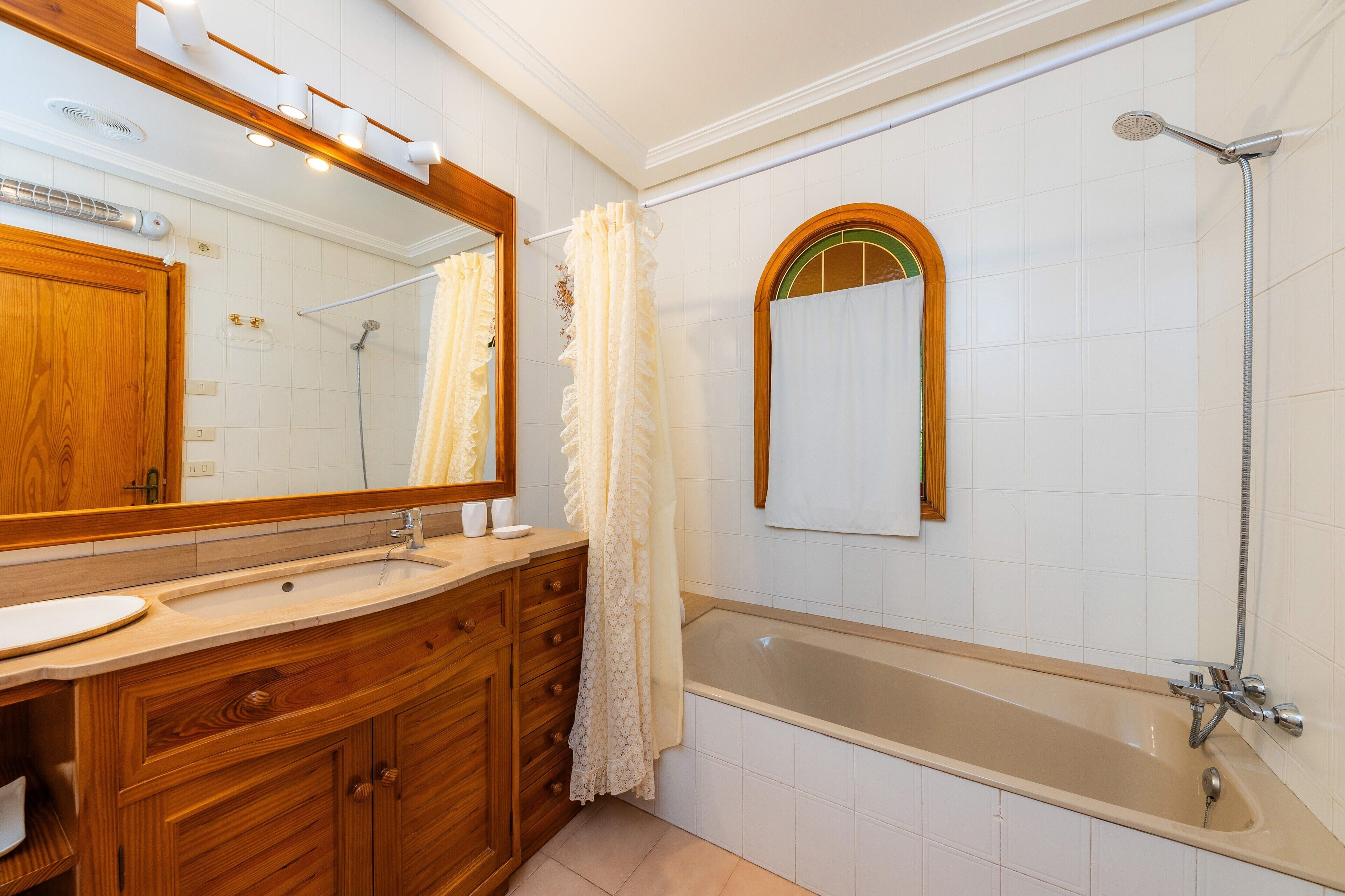A bathroom with a wooden vanity, a large mirror, a bathtub, and a shower.