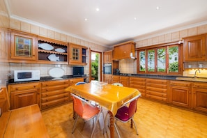 Una cocina con armarios de madera, microondas, lavabo y una mesa de comedor con sillas.