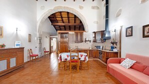 Una cocina amplia con comedor, un sofá rojo y un arco de piedra.