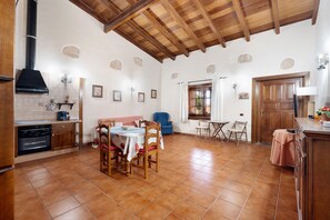 A spacious kitchen with a dining area, wooden ceiling beams, and tiled flooring.