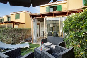 Un patio con mobiliario exterior, puerta de vidrio y vista del edificio contiguo.