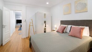 Un dormitorio con una cama, mesitas de noche, un armario y dos obras de arte colgadas en la pared.