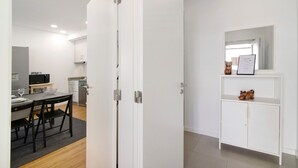 Una cocina moderna con armarios blancos, un comedor con mesa y sillas, y un aparador blanco con un espejo y adornos.
