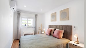 A bedroom with a bed, bedside tables, a window, and artwork on the wall. - Apartment "Telmus Villa 1 Andar" with Sea View, Private Terrace & Wi-Fi (Monte Gordo)