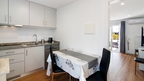 A modern kitchen with white cabinets, a granite countertop, and a dining area with a table set for two. - Apartment "Telmus Villa 1 Andar" with Sea View, Private Terrace & Wi-Fi (Monte Gordo)