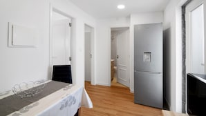 A modern kitchen with a stainless steel refrigerator, wooden flooring, and white walls. - Apartment "Telmus Villa 1 Andar" with Sea View, Private Terrace & Wi-Fi (Monte Gordo)