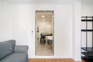 Une pièce avec un canapé gris, une table à manger avec des chaises et une étagère en métal noir.