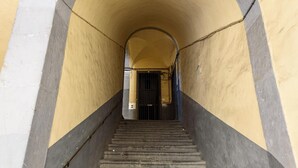 A staircase leading to a door at the end of a corridor with yellow and gray walls. - Vico Sedil Capuano 21 - Appartamento 1 (Naples)
