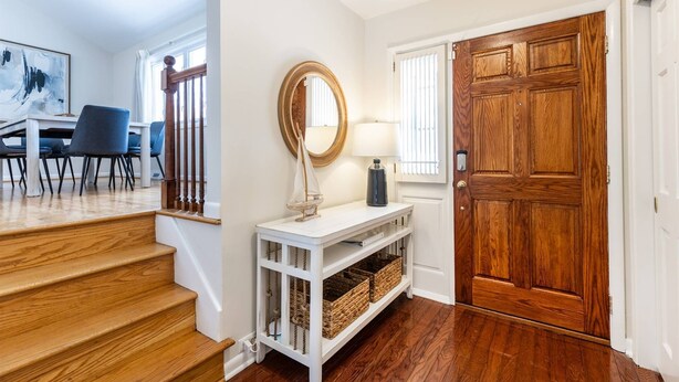 Un escalier en bois mène à un palier où se trouvent une console blanche, un miroir et des paniers en osier.
