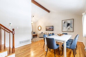 A dining area with a white table and blue chairs, a wooden staircase, and a painting on the wall. - Game Days & Family Stays at Dog-Friendly Home Near Navy Stadium w Private Fenced-In Yard (Annapolis)