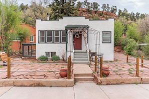 Situated in a serene landscaped area, this single-story building features a charming entrance with a red door and a cozy porch.