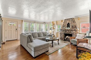 A living room with a stone fireplace, a gray sectional sofa, and a wooden coffee table. - Idyllic retreat near the Incline, nestled in Manitou’s breathtaking landscapes.  (Manitou Springs)
