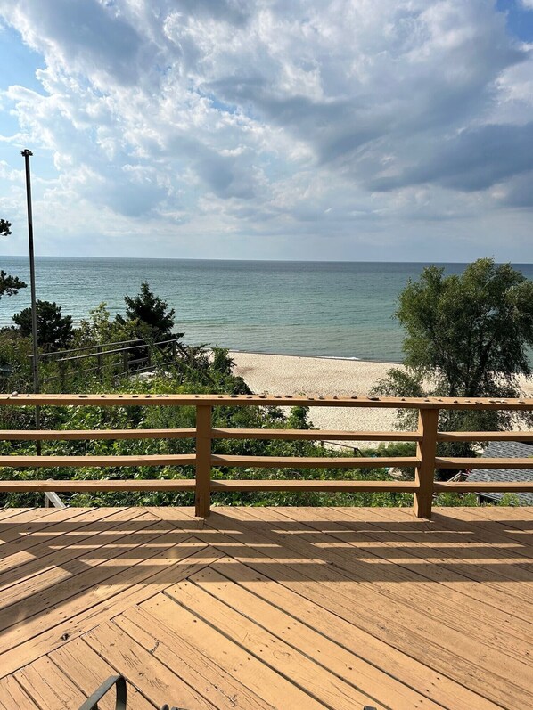 Cubierta de madera con vista a una playa y al mar, bajo un cielo nublado.
