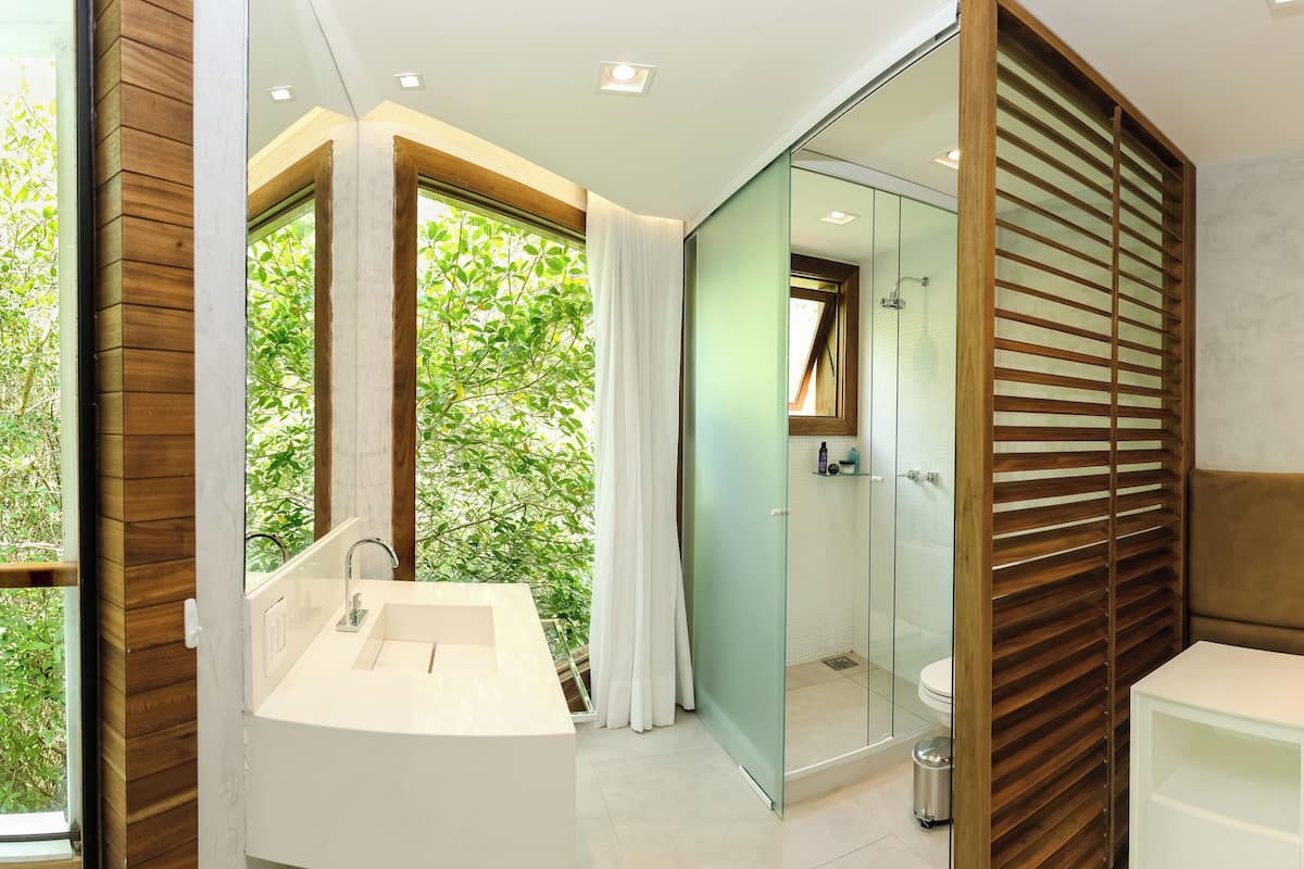 A modern bathroom with a glass-enclosed shower, a white sink, and a wooden vanity.